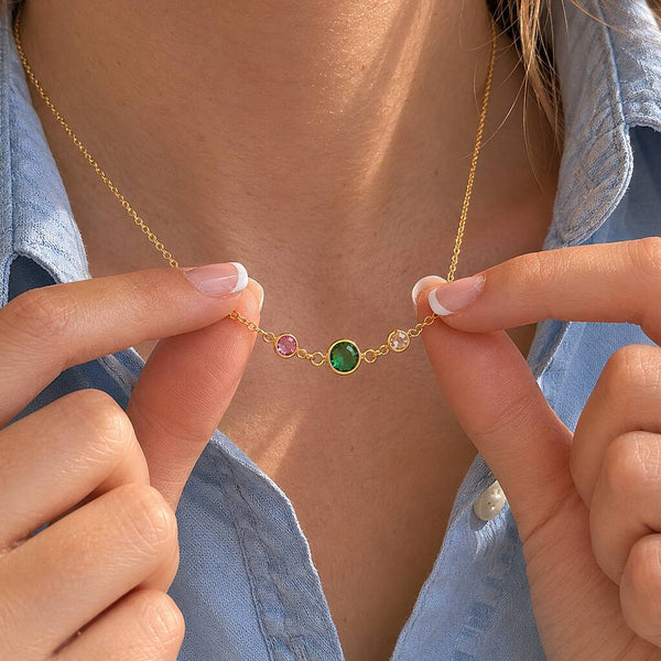 Gold birthstone link necklace with emerald centre stone and two smaller crystals, styled for everyday layering