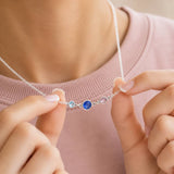 Silver birthstone necklace featuring three bezel-set crystals, held to highlight the meaningful family design