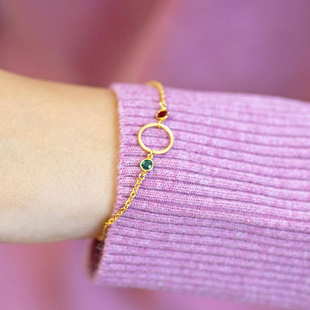Close-up of a gold plated circle bracelet with two colourful birthstones for modern layered bracelet styling