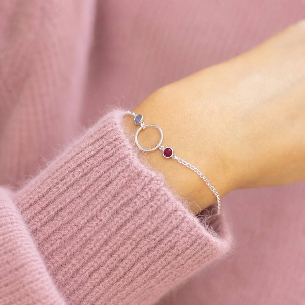 Silver plated circle birthstone bracelet layered on the wrist with two colourful crystals for a meaningful everyday look