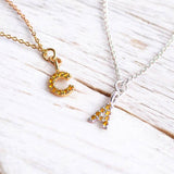 Image shows a gold initial 'C' November birthstone necklace and a silver initial 'A' November birthstone necklace.