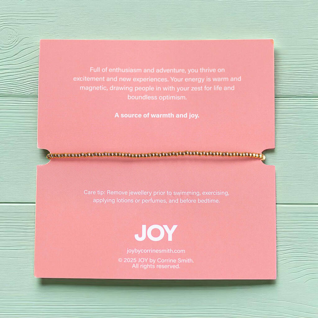 Bracelet backing card with healing message, gold beaded bracelet, and JOY branding on pink card with crystal accents