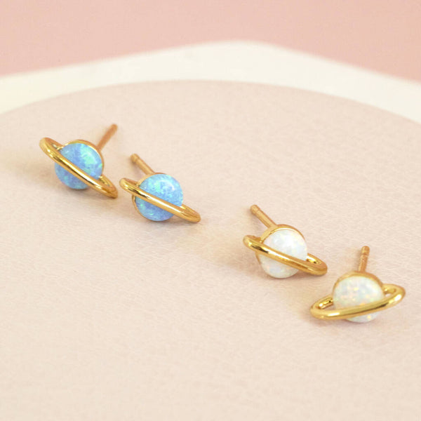 Image shows Out of this World Opal Planet Earrings from left to right: blue opal studs and white opal studs on a pink backdrop
