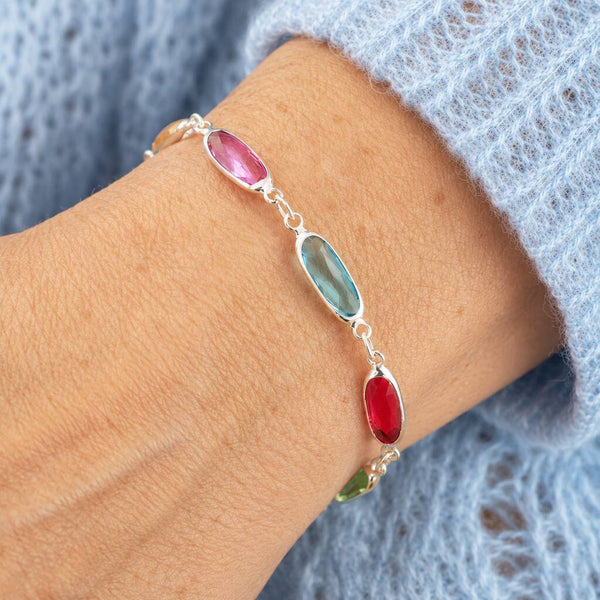 Silver oval link birthstone bracelet with pink, blue and red crystal details, elegant everyday layering jewellery.