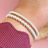 Model wears Set of Two Pearl Bracelets larger size on top smaller size on bottom.