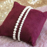Image shows Set of Two Pearl Bracelets on a maroon jewellery pillow - larger size on left, smaller size on right.
