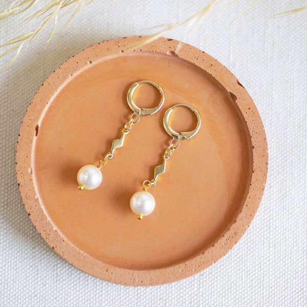 Image shows Pearl Drop Earrings with Lightning Bolt Detail on a terracotta dish.