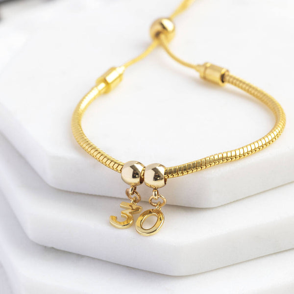 Image shows Personalised Gold Plated Birthday Charm Slider Bracelet on a white backdrop.