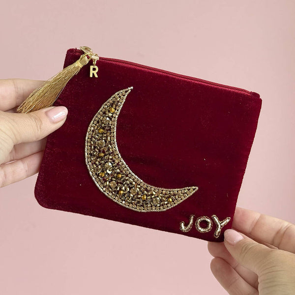 Close-up of velvet beaded pouch showing intricate hand beaded moon design with gold initial charm.