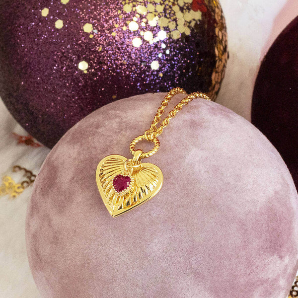 Image shows Ribbed Heart Necklace with January Birthstone Detail on a pink backdrop.
