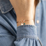 Rose gold friendship knot bangle with initial and birthstone charms, delicate stacking jewellery for everyday style.
