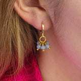 Model wears Shades of Blue Huggie Hoop Charm Earrings in light blue-grey.