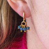 Model wears Shades of Blue Huggie Hoop Charm Earring in indigo.