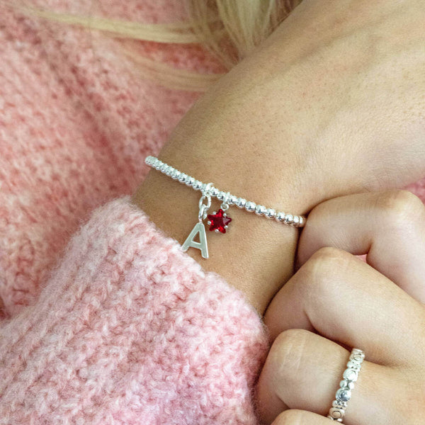 Model wears Silver Plated Initial and Birthstone Star Bracelet with initial 'A' and July Ruby star birthstone