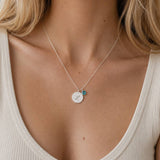 Silver plated initial disc necklace styled with a teal birthstone charm for a colourful everyday layered jewellery look