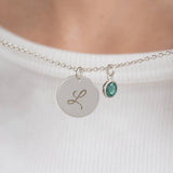 Silver plated script initial disc necklace with a teal birthstone charm, a timeless personalised everyday necklace