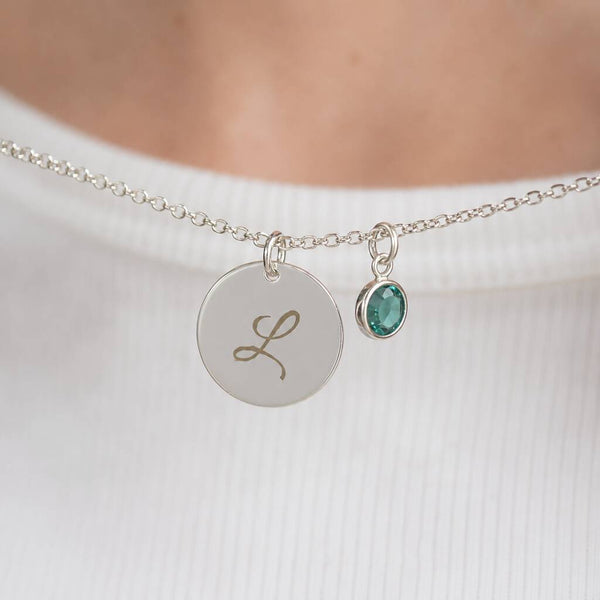 Silver plated script initial disc necklace with a teal birthstone charm, a timeless personalised everyday necklace