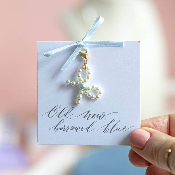 pearl bow charm with blue pearl in the centre attached to a blue ribbon bow on an old, new, borrowed, blue sentiment card 