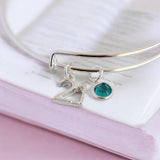 Silver birthday charm bangle featuring a 21 pendant and teal birthstone crystal detail