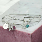 Silver charm bangle with initial disc, birthday number charms and pink and teal birthstone crystals