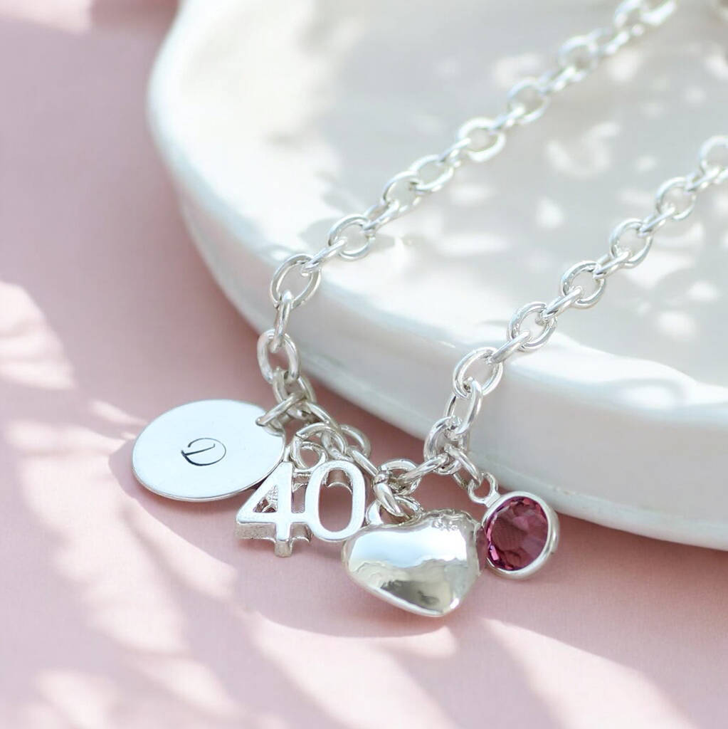 Silver charm bracelet featuring a 40 pendant, heart charm and pink crystal birthstone detail