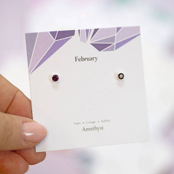 Purple February birthstone stud earrings in sterling silver, displayed on a colourful amethyst jewellery card.
