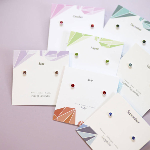 Colourful sterling silver birthstone studs in ruby, sapphire and other shades, displayed on monthly jewellery cards.
