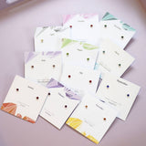 Rainbow birthstone stud earrings in sterling silver, arranged on colourful month cards from January to November.
