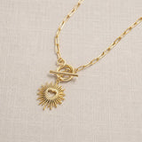Gold plated T bar necklace with a sunburst heart charm, modern layering jewellery with a polished finish.