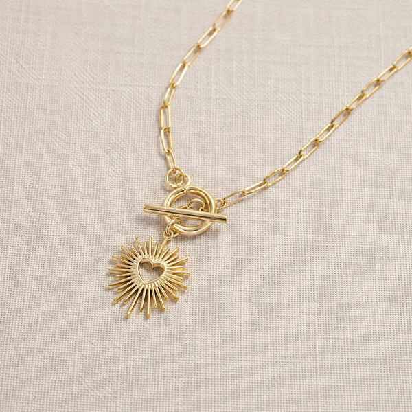 Gold plated T bar necklace with a sunburst heart charm, modern layering jewellery with a polished finish.