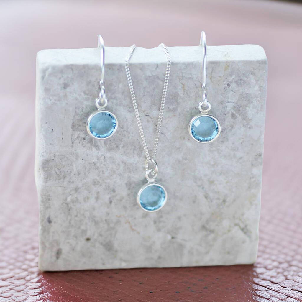 image shows Swarovski crystal birthstone jewellery using aquamarine 0.6cm birthstones displayed on a grey marble block on a pink backdrop