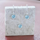 image shows Swarovski crystal birthstone jewellery using aquamarine 0.6cm birthstones displayed on a grey marble block on a pink backdrop