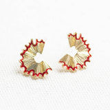 Close-up of gold pencil shaving stud earrings with red enamel detail, playful statement earrings for everyday styling