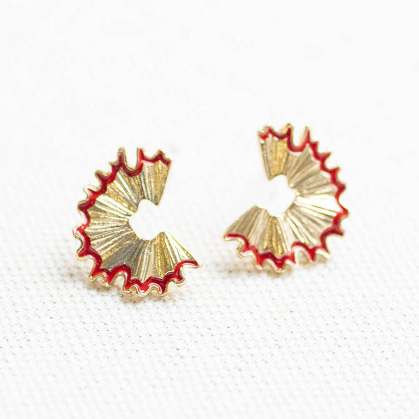 Close-up of gold pencil shaving stud earrings with red enamel detail, playful statement earrings for everyday styling