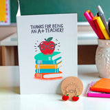 Thank You Teacher card with illustrated apple and stack of books, paired with red apple enamel drop earrings.