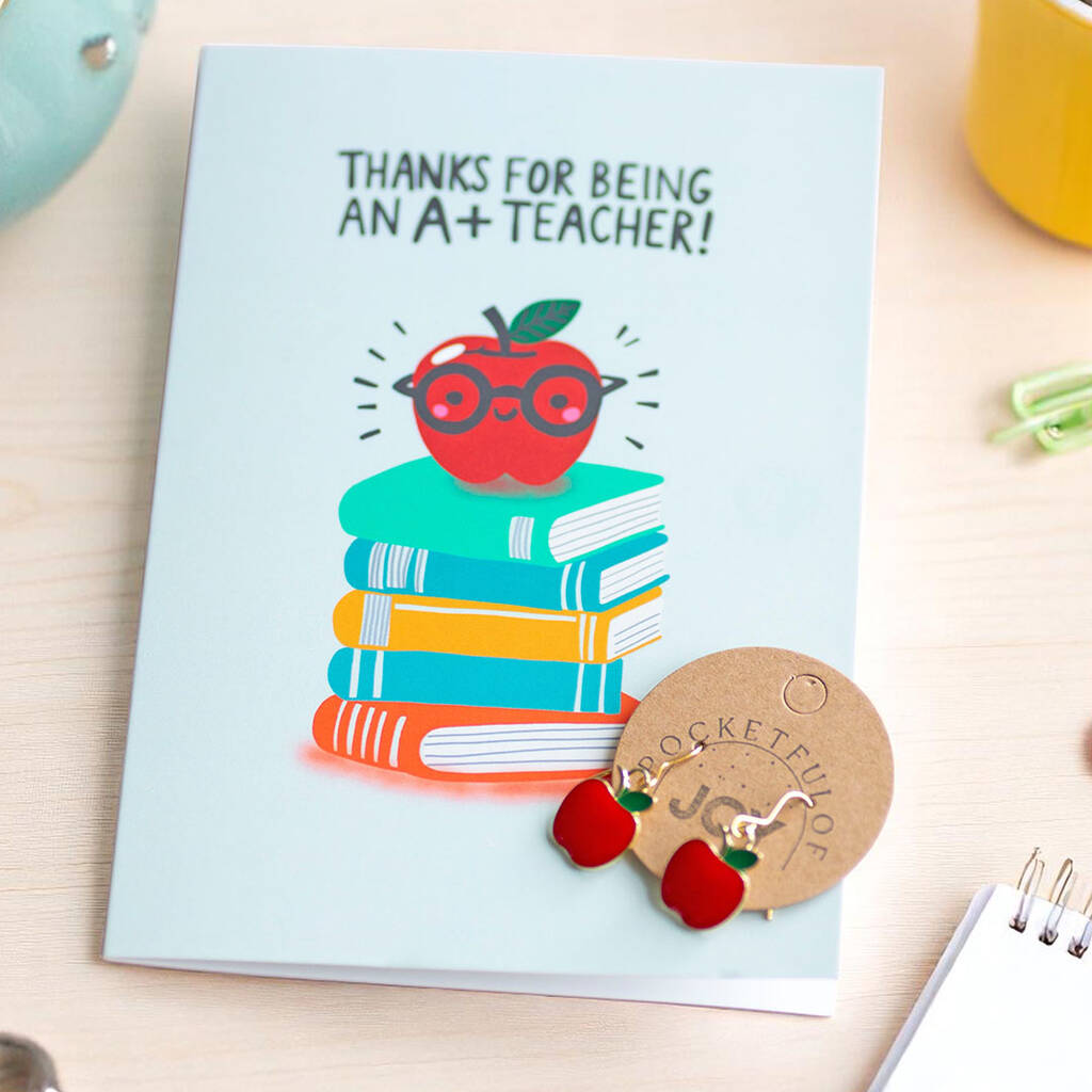 Close-up of Thank You Teacher card and red apple earrings displayed on a desk