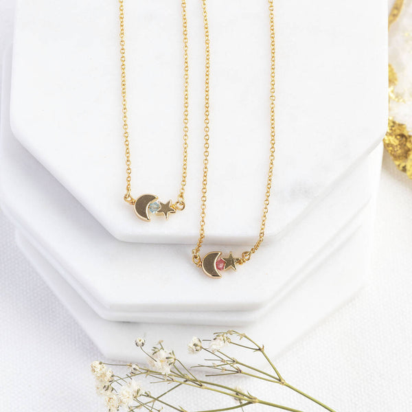 Image shows two Tiny Moon and Star Necklaces with Birthstone Detail from left: March Aquamarine and October Rose. Sitting on a white backdrop.