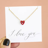 Image shows gold plated Tiny Red Enamel Floating Heart Necklace on an 'I love you' sentiment card.
