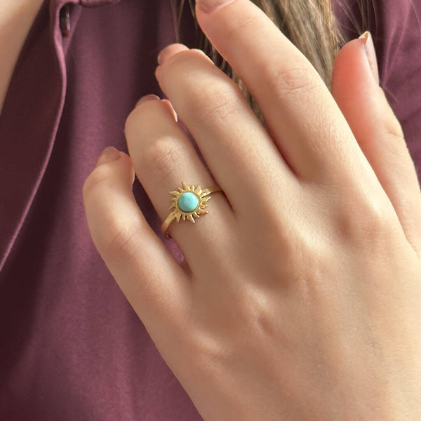 Image shows model in burgundy blouse wearings a turquoise gemstone sun ring