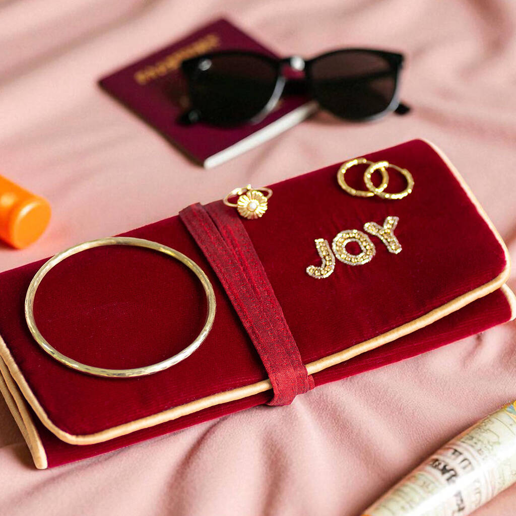 Maroon velvet travel jewellery roll beaded with gold ‘JOY’ lettering, tied with a matching ribbon.