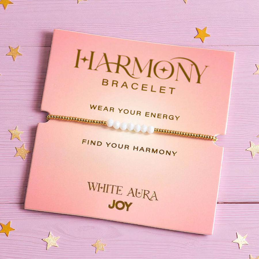 White Aura Joy bracelet with gold beads, displayed on pink card reading 'Find Your Harmony' and 'Wear Your Energy