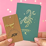 Close-up of gold Scorpio star sign necklace with matching celestial notebook