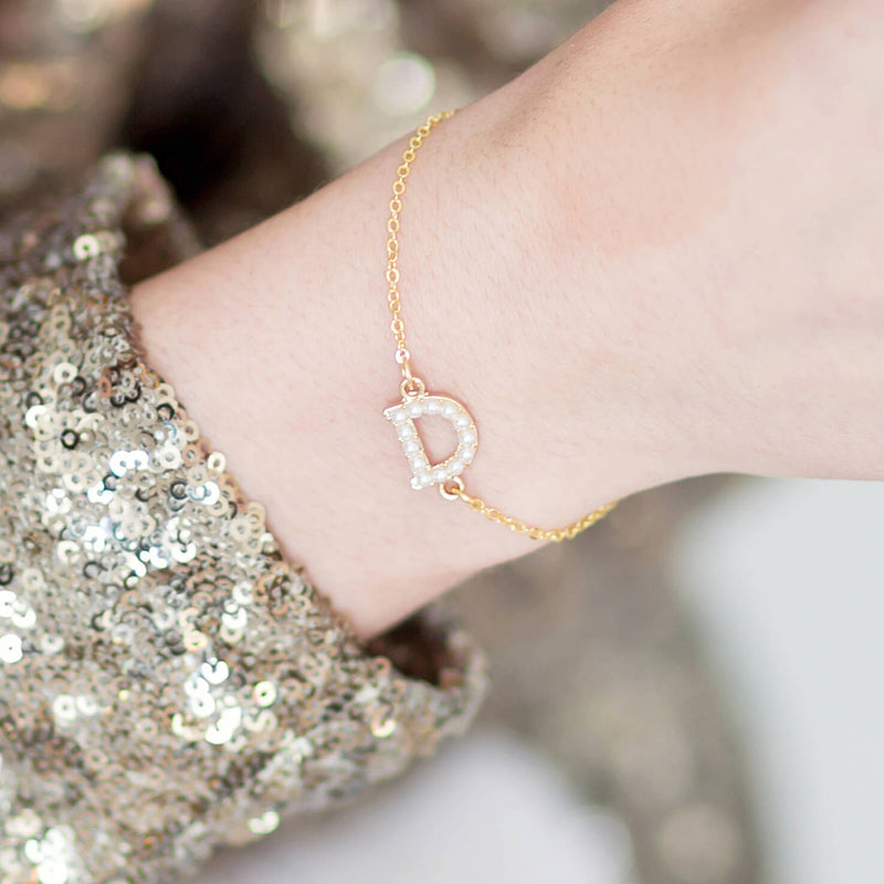 Models wears the personalised pearl initial bracelet on a gold chain with the pearl initial D