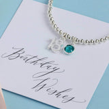 Image shows silver plated 18th birthday beaded birthstone charm bracelet with an '18' charm and a December blue zircon Swarovski birthstone crystal. Pictured with a 'birthday wishes' sentiment card.