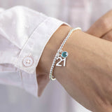 Model wears silver plated 21st birthday birthstone charm bracelet with a '21' charm and a December Blue Zircon Swarovski Charm