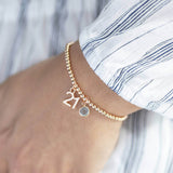 Model wears rose gold plated beaded bracelet with '21' charm and a March Aquamarine Swarovski Birthstone.