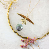 Image shows one of a kind capella necklace with half moon phase. on a white backdrop.