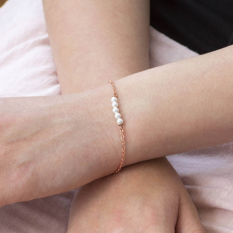 Model wears delicate Swarovski pearl bracelet in rose gold plated brass, with five dainty white pearls.