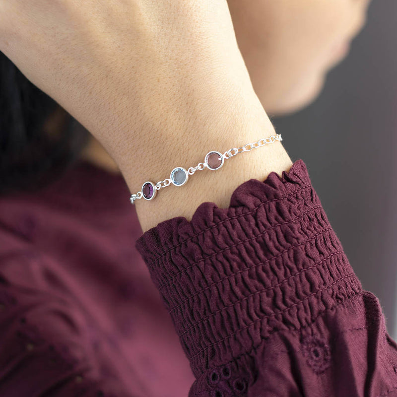 Model wears silver Family Birthstone Link Bracelet with three Swarovski Birthstone Gems (up to 10 can be selected) in Amethyst, Aquamarine and Light Amethyst for February, March and June.