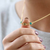Model wears gold plated Family Birthstone Link Necklace with three birthstones, blue zircon, peridot and emerald for the months December, August and May.